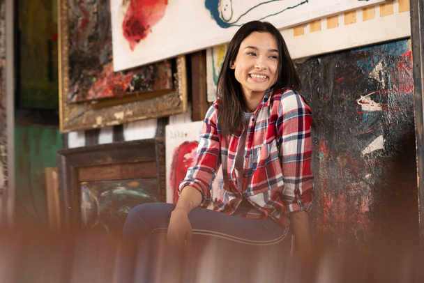 mladá krásná žena sedí na židli v červené kostkované košili ve studiu - Fotografie, Obrázek