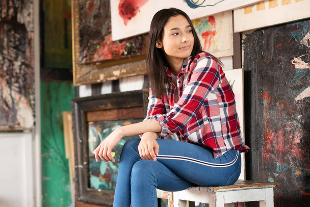 young beautiful woman posing in a red shirt in the studio, sitting - Foto, Imagen