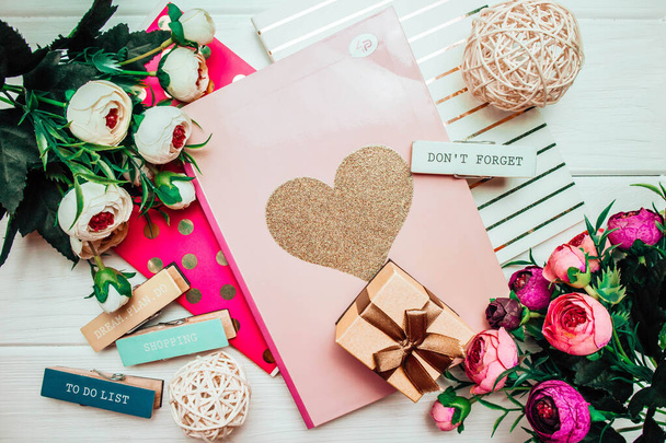 Hermosos y rosados cuadernos y flores sobre un fondo de madera blanca con pinzas de ropa y regalo en primavera. Primavera fotografía - Foto, imagen