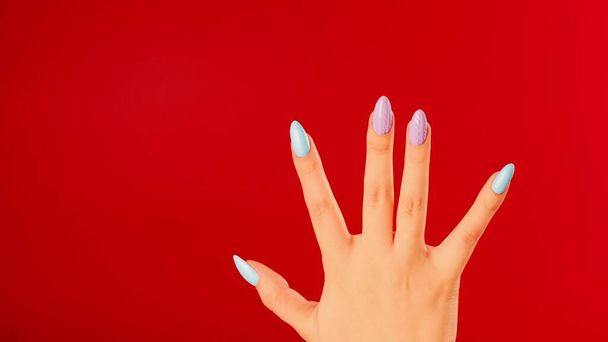 Woman's hand with beautiful nails on red background. Unrecognizable person shows manicure. Close up. Concept of care and beauty - Foto, Imagem
