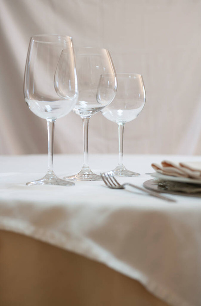Un tavolo da pranzo apparecchiato per mangiare. Bicchiere da vino, bicchiere d'acqua, piatto, forchetta, coltello, tovagliolo, tovaglia. - Foto, immagini