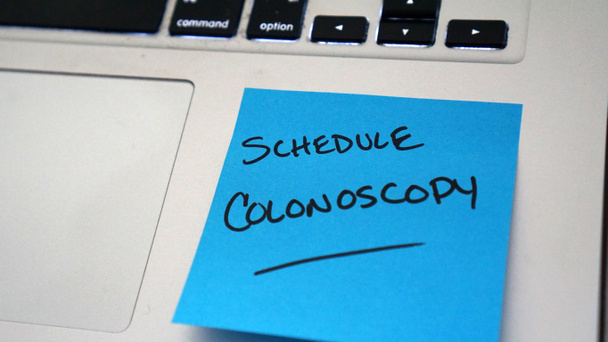Przyklejone przypomnienie na laptopie, żeby zaplanować kolonoskopię. Marzec jest Colorectal Cancer Awareness miesiąc.     - Zdjęcie, obraz