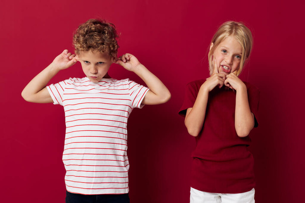 Симпатичные стильные детские эмоции стоят бок о бок в повседневной одежде красный фон - Фото, изображение
