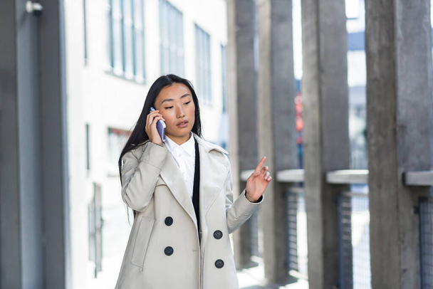 Beautiful and happy asian woman talking on the phone, chinese woman walking during a break near the office, business woman successful - Фото, зображення