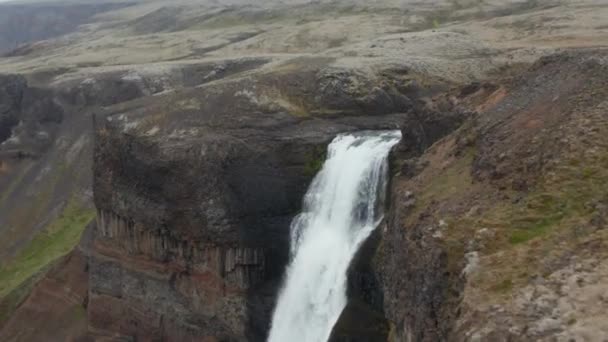 Slide e pan tiro de água rolando sobre a borda da rocha e caindo ao longo do penhasco. Incrível natureza nórdica preservada. Haifoss, Islândia - Filmagem, Vídeo