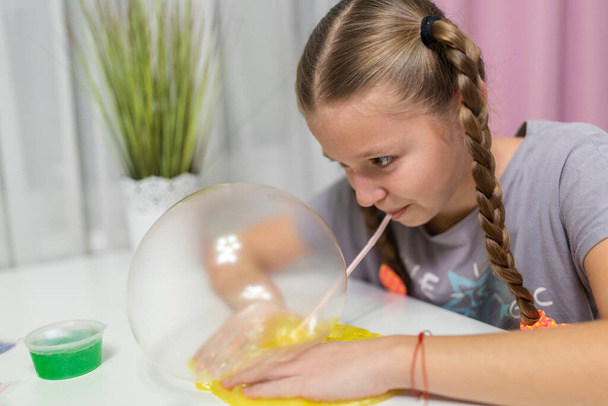 girl play with yellow slime inflates bubble fun at home - Photo, image