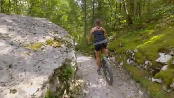 Mladá žena turista jezdí na elektrickém kole podél malebné lesní stezky v Bovci - Záběry, video