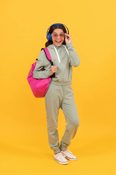 здивована дитина в навушниках носить рюкзак. повернутися до школи. знання та освіта
. - Фото, зображення