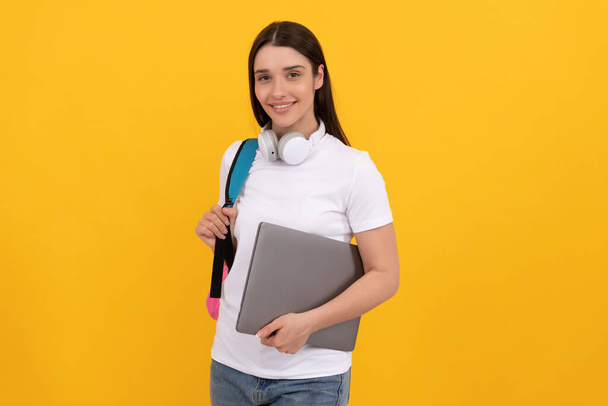 happy woman with earphones and computer on yellow background, school - Photo, image