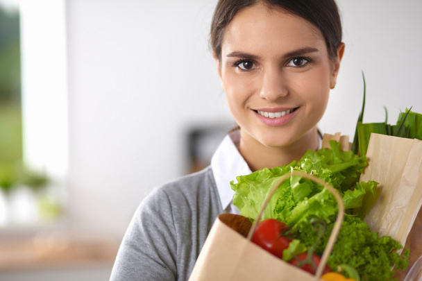 Young woman holding grocery shopping bag with vegetables Standing in the kitchen. - Foto, Bild