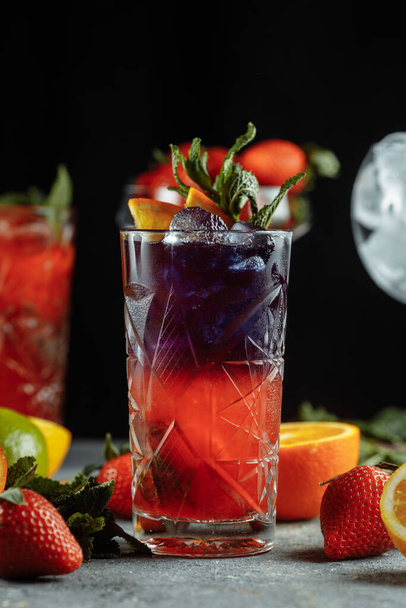 Coloridas bebidas refrescantes para el verano, jugo de limonada de fresa fría con cubitos de hielo en los vasos adornados con limones frescos en rodajas. - Foto, imagen