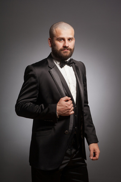 Stylish and brutal bald man with a beard in elegant black suit - Zdjęcie, obraz