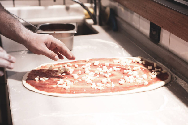 pizza chef mettre la sauce sur la base dans une cuisine commerciale - Photo, image