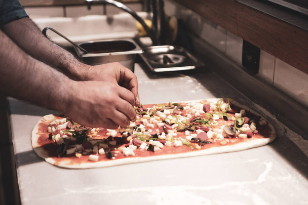 Pizza chef put sauce on base in a commercial kitchen - 写真・画像