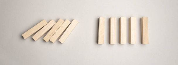 O papel corta a silhueta de um homem parando de cair dominós em uma imagem conceitual. Sobre fundo cinza. - Foto, Imagem