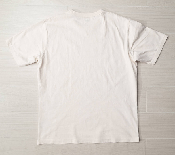Plantilla de maqueta de camiseta beige en blanco en el suelo. - Foto, imagen