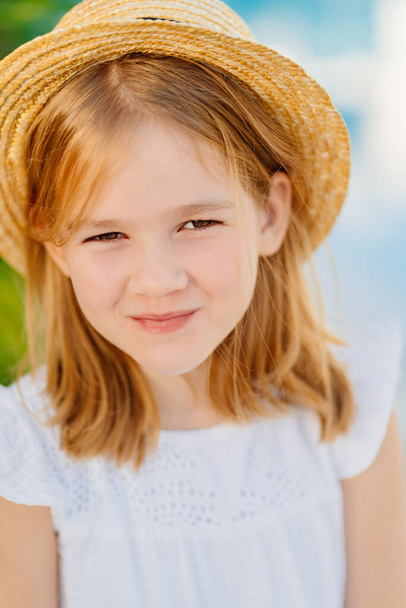 portrait of a cute little girl with blonde hair in a straw hat.  - 写真・画像