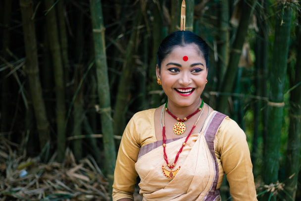 Mädchen lächelndes Gesicht isoliert gekleidet in traditionellen Tragen auf dem Festival mit verschwommenem Hintergrundbild wird anlässlich des bihu at assam india aufgenommen. - Foto, Bild
