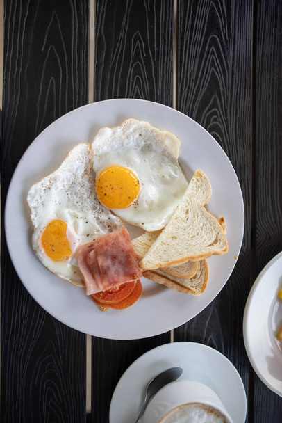 Lahodná snídaně se smaženými vejci a šálkem kávy na černém stole - Fotografie, Obrázek