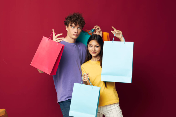 teenagers in colorful T-shirts with bags Shopping red background unaltered - Fotoğraf, Görsel