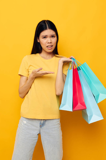 woman in a yellow T-shirt with multicolored shopping bags isolated background unaltered - Foto, Imagem