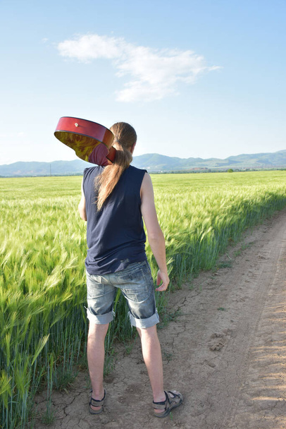 campo de trigo verde y un hombre con una guitarra, - Foto, Imagen
