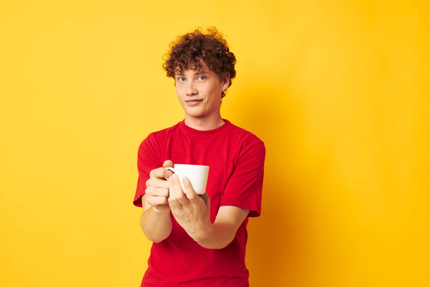 guy with red curly hair white mug in the hands of a drink yellow background unaltered - Photo, image