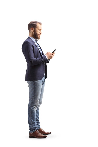 Full length profile shot of a man in suit and jeans typing on a mobile phone isolated on white background - Foto, Bild