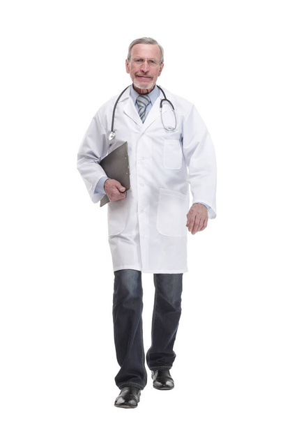 full lenth of a mature doctor is walking and holding on the clipboard - Foto, Imagen