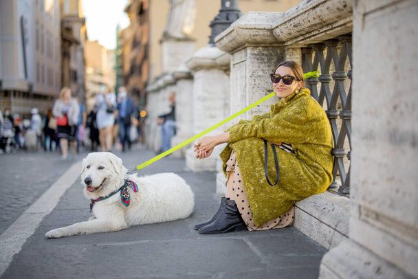 Жінка з білим собакою сидить на вулиці в Римі. - Фото, зображення