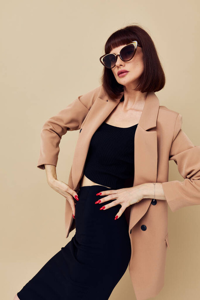 beautiful woman in a beige jacket elegant style sunglasses light background - 写真・画像