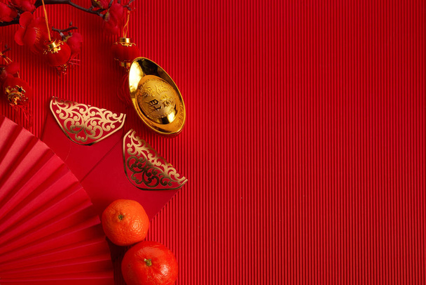 Chinese new year festival decorations. Orange, red packet, plum blossom and lucky money on red background. Translation: let ten thousand wishes come true. - Photo, image