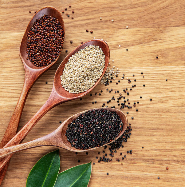 Punaiset, mustat ja valkoiset kvinoan siemenet puupohjalla - Valokuva, kuva