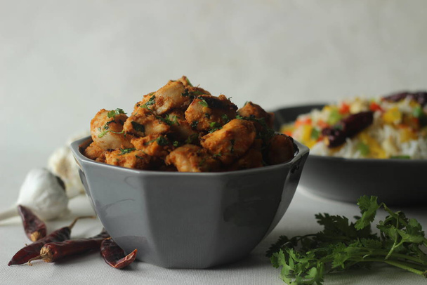 Chilli garlic chicken bites. A pan fried chicken dish with a strong garlic flavour. Served with Steamed basmati rice tossed with sauteed bell peppers flavoured with red chillies and garlic. - Photo, Image
