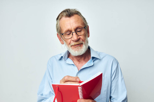 Portrait of happy senior man red notepad writing light background - Φωτογραφία, εικόνα