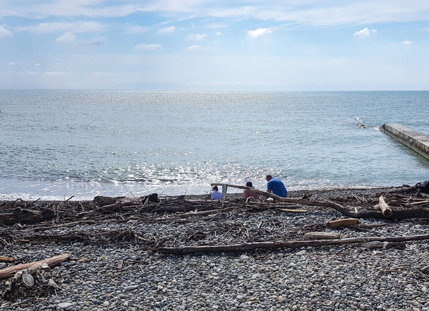 Komunita ekologů společně třídí a odstraňuje odpadky na pláži, sedí na pobřeží. - Fotografie, Obrázek