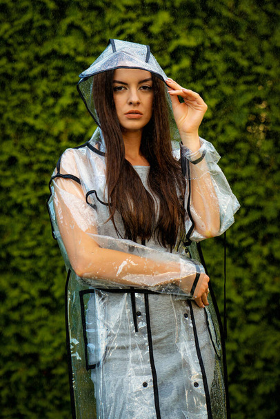 Young beautiful woman in hooded raincoat on rainy day - Foto, afbeelding