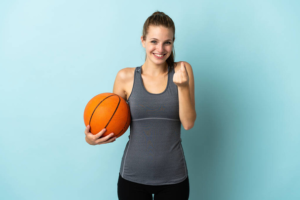 Jovem mulher jogando basquete isolado no fundo azul fazendo gesto de dinheiro - Foto, Imagem
