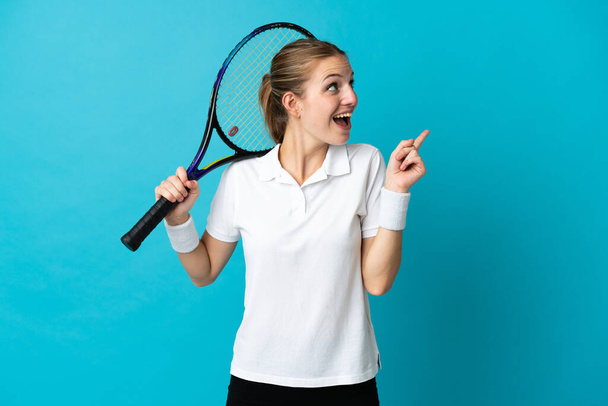 Fiatal nő teniszező elszigetelt kék háttér azzal a szándékkal, hogy megvalósítsa a megoldást, miközben felemeli az ujját - Fotó, kép