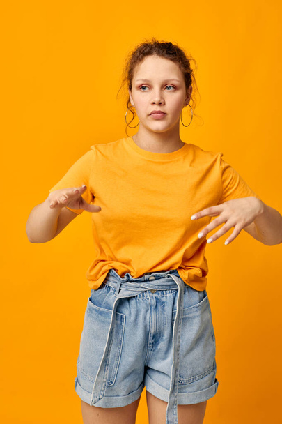 cheerful woman in a yellow t-shirt posing emotions yellow background unaltered - Foto, afbeelding