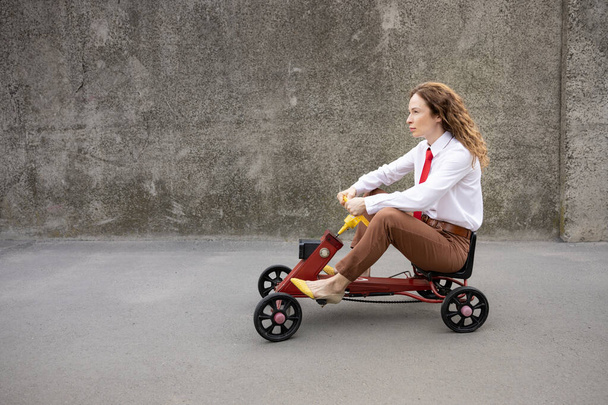 Portrait of funny businesswoman outdoor. Woman driving retro pedal car. Back to work, start up and business idea concept - Foto, immagini