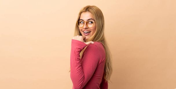 Young Uruguayan blonde woman over isolated background pointing to the side to present a product - Foto, afbeelding