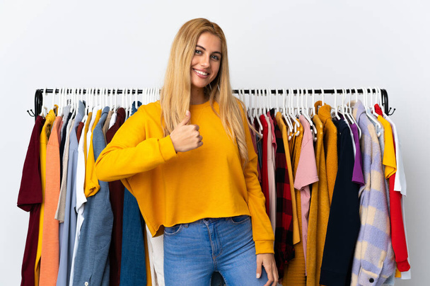 Jeune femme blonde uruguayenne dans un magasin de vêtements donnant un pouce geste - Photo, image