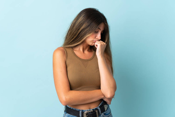 Young caucasian woman isolated on blue background having doubts - Foto, afbeelding