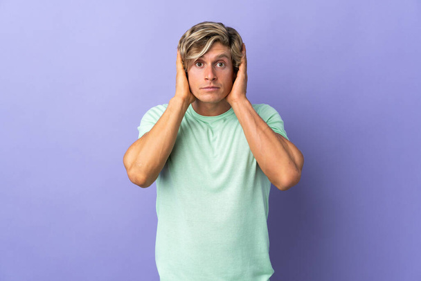 Английский человек на изолированном фиолетовом фоне разочарован и закрывает уши - Фото, изображение