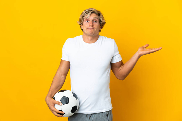Jugador de fútbol inglés sobre fondo amarillo aislado que tiene dudas mientras levanta las manos - Foto, Imagen