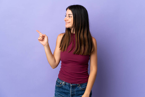 Mladá běloška žena izolované na fialovém pozadí ukazující prstem na stranu - Fotografie, Obrázek