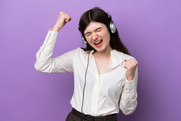 Telemarketer Russian woman working with a headset isolated on purple background celebrating a victory - Фото, зображення