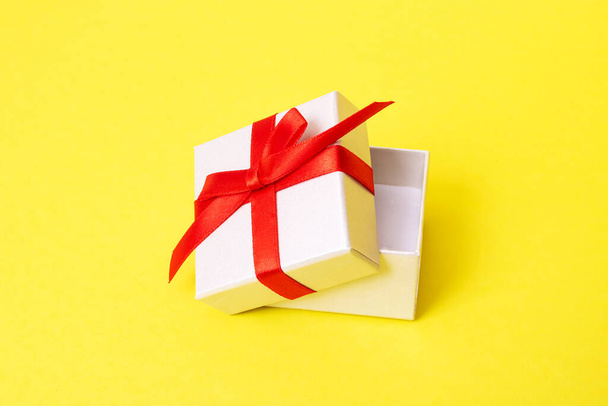 Sarı arka planda bir hediye olan beyaz kutu. - Fotoğraf, Görsel