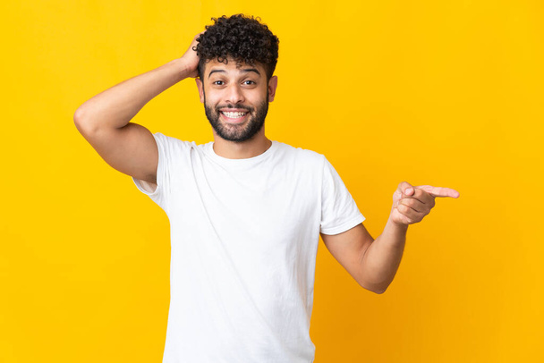 Young Moroccan man isolated on yellow background surprised and pointing finger to the side - Fotografie, Obrázek